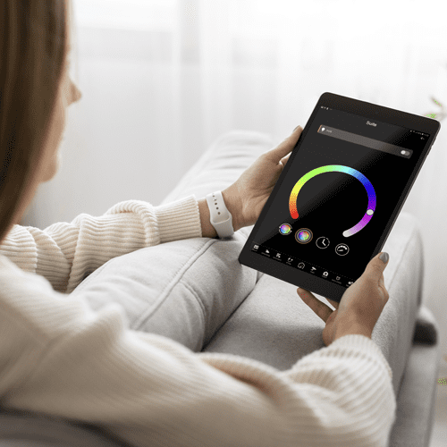 Pessoa no sofá a controlar a iluminação da casa num tablet