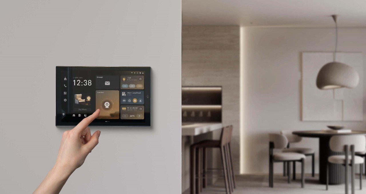 Mão a tocar num monitor interior Hikvision com controlo de luzes, alarme e ar condicionado